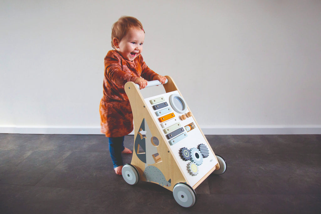 Petit garçon qui marche avec le chariot d’activités bébé en bois avec jeux d’éveil
