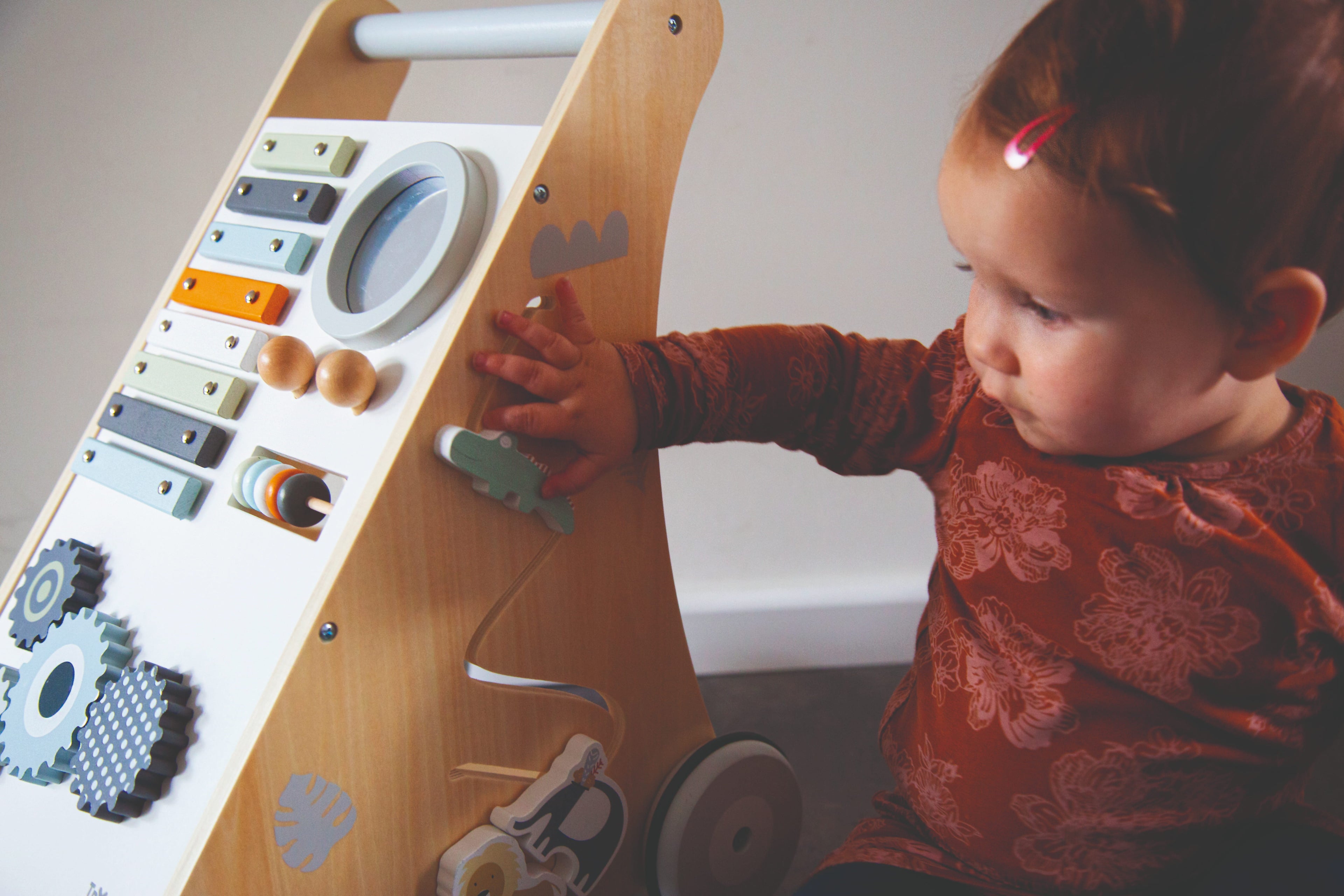 Enfant qui joue avec l'engrenage du chariot d’activités bébé en bois avec jeux d’éveil
