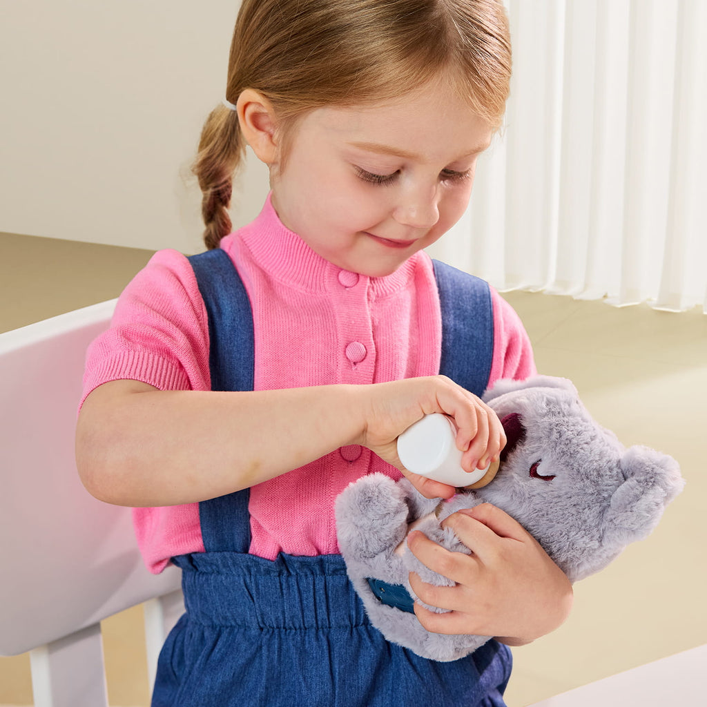 Petite fille qui donne le biberon à la peluche interactive bébé koala avec cœur lumineux
