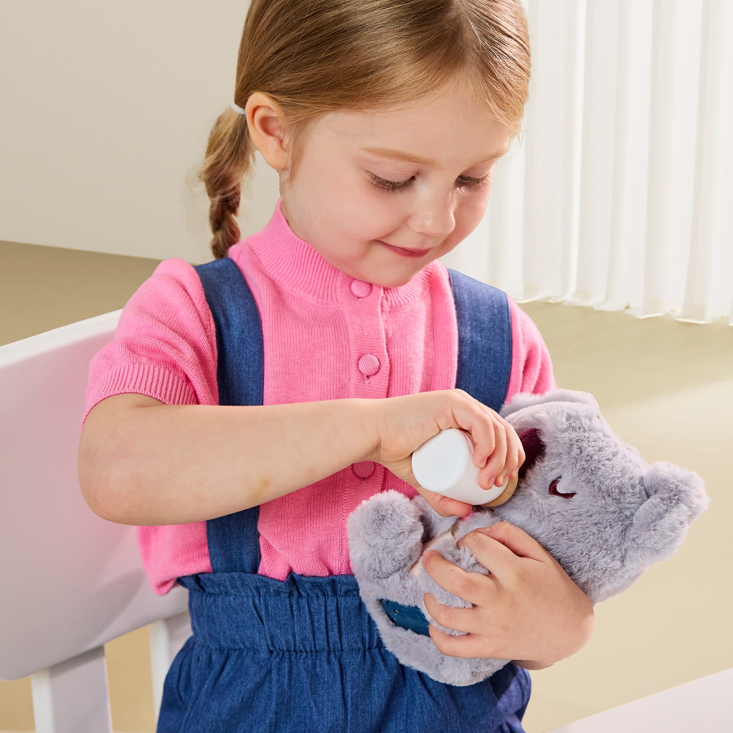 Petite fille qui donne le biberon à la peluche interactive bébé koala avec cœur lumineux
