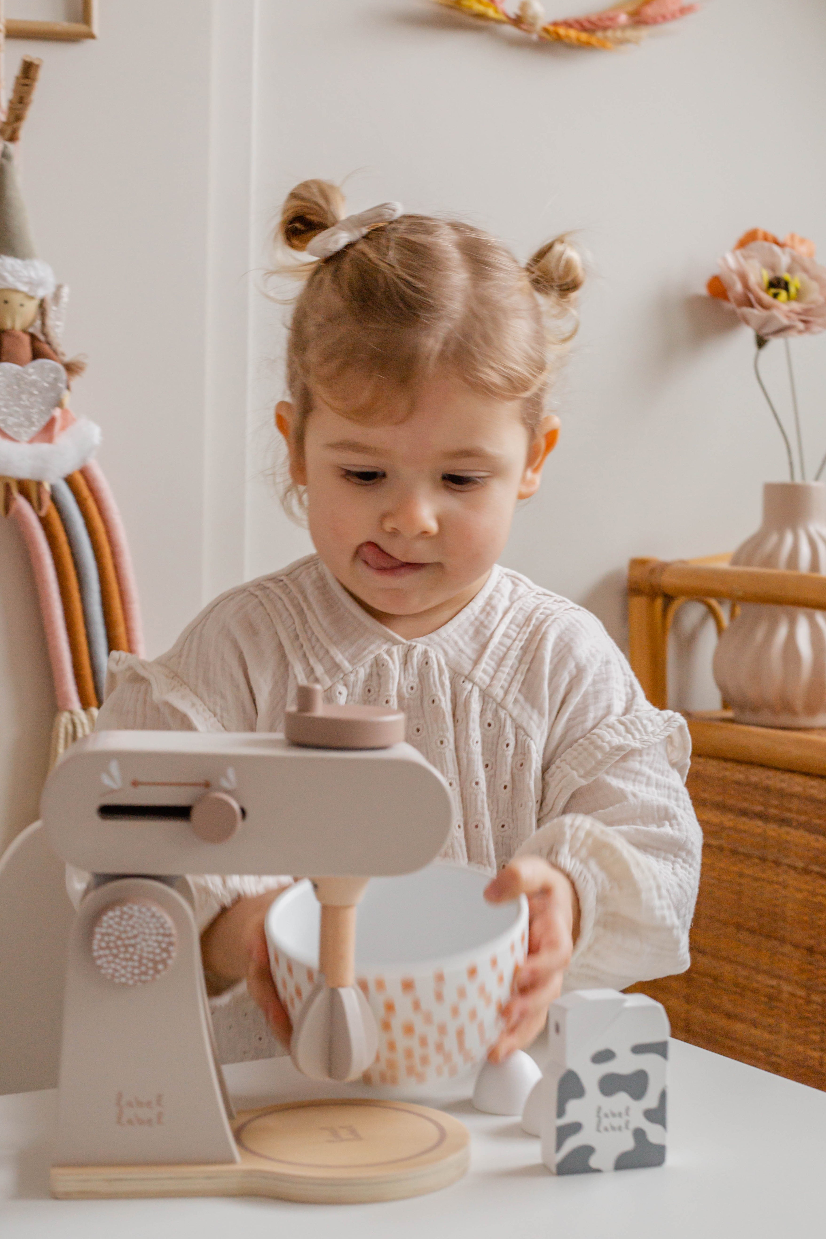 Petite fille qui met un bol sous le robot culinaire enfant en bois avec accessoires cuisine